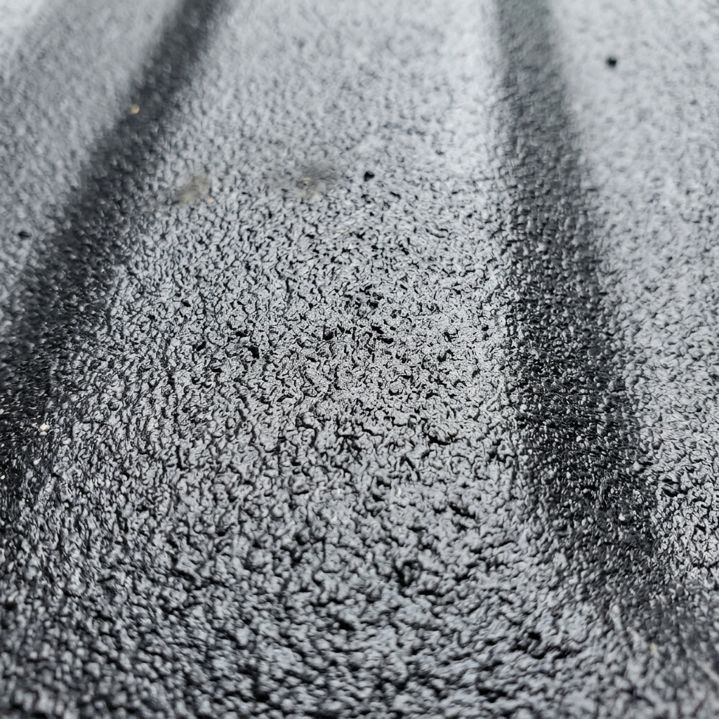Close-up of a textured black surface with rough, uneven patterns and shadowed areas